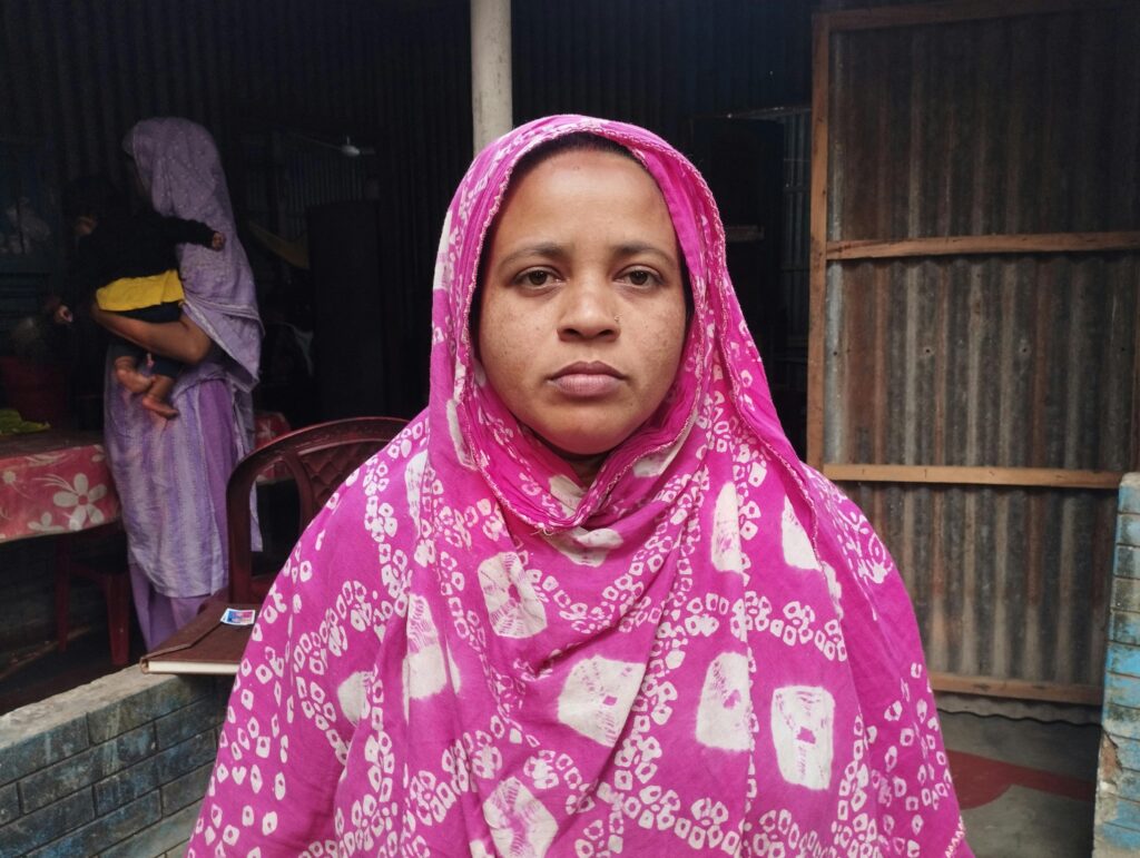 Woman in pink hijab standing indoors, medium close-up portrait.